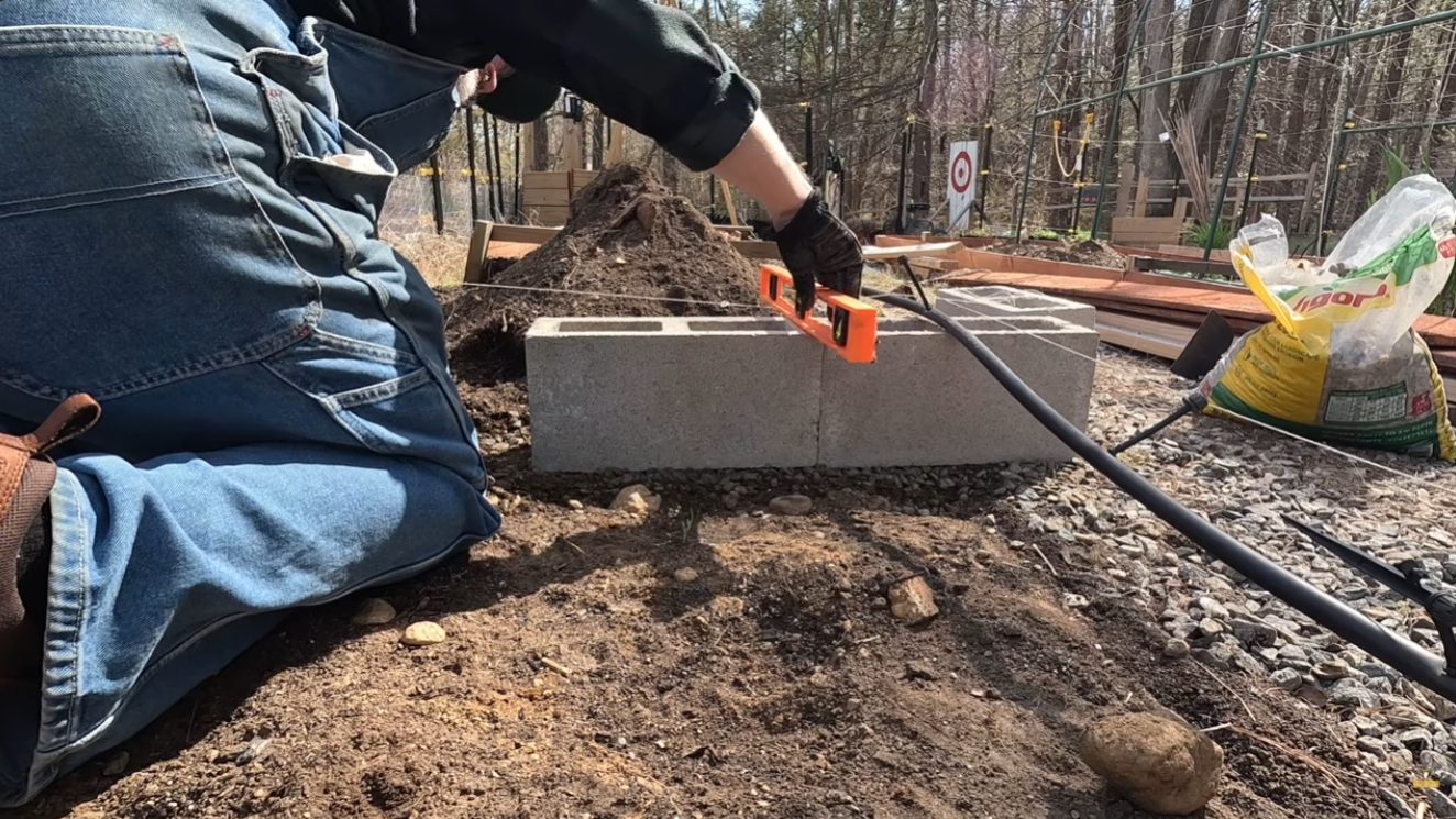 Checking the first course of concrete block for level with a torpedo level