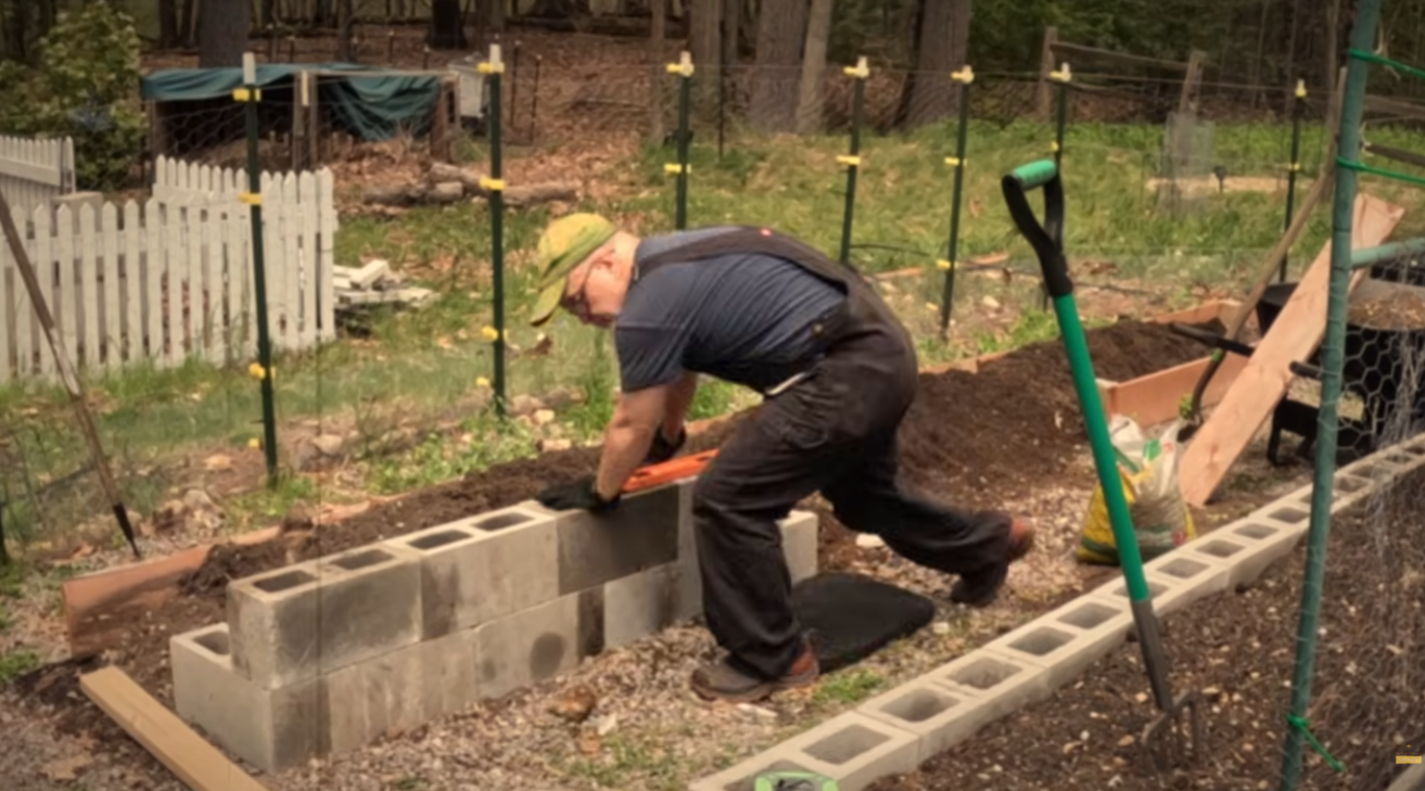 Setting a concrete block into place while building the raised bed wall